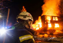 Firefighter watches burning building at night scene