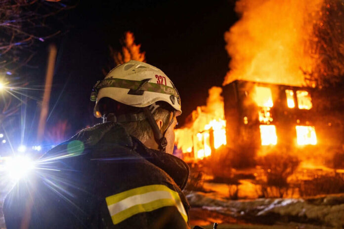 Firefighter watches burning building at night scene