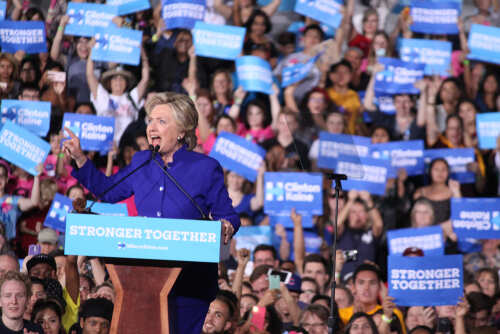 Hillary Clinton speaking at a political rally with a cheering crowd