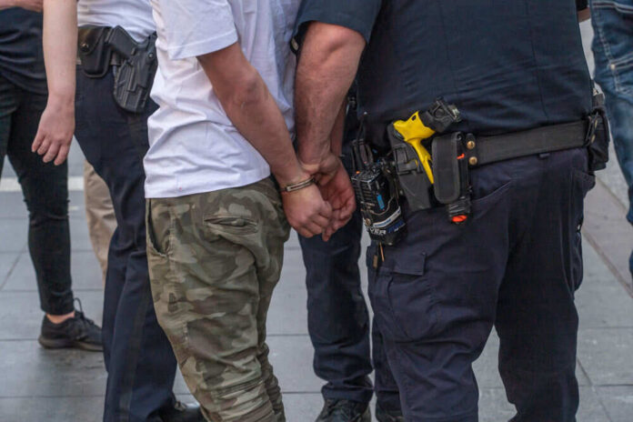 1977146003 Person handcuffed by police on the street