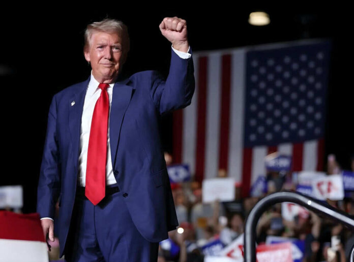 2551890211 Man in suit raises fist at event with crowd