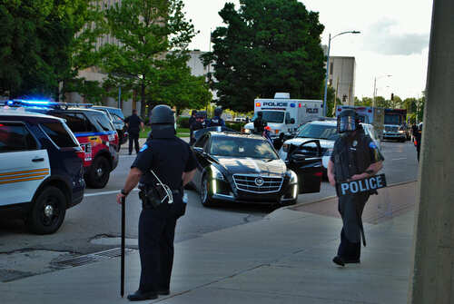 Police officers in riot gear managing a scene with emergency vehicles