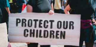 Person holding sign reading Protect Our Children