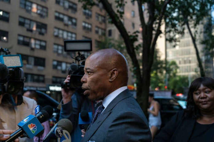 Man speaking to media outside surrounded by cameras