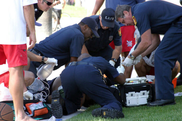Emergency responders assisting person on grass lawn