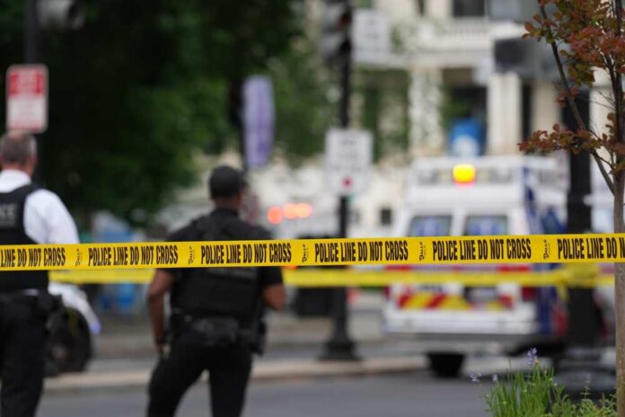 shutterstock_2622588825.jpg Police officers near a crime scene marked by caution tape