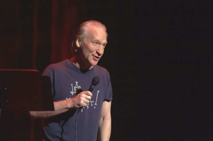 Man holding microphone wearing dark shirt on stage