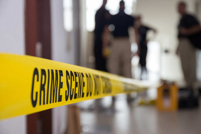 Yellow crime scene tape with blurred figures in the background