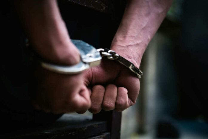 Hands in handcuffs behind back closeup