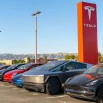 Tesla cars parked near red Tesla sign