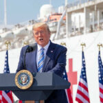 Trump’s Dramatic Oil Crackdown: Coast Guard Strikes Man speaking at podium with flag background