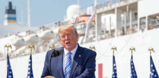Man speaking at podium with flag background