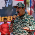 Man in camouflage uniform speaking at event outdoors
